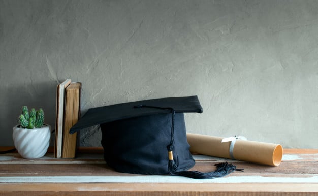 graduation-cap-hat-with-degree-paper-wood-table_43379-51