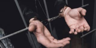 man-handcuffs-bars-police-station_85574-1297