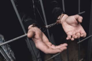 man-handcuffs-bars-police-station_85574-1297