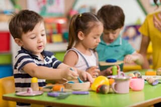 Childs are playing with play clay in classroom.