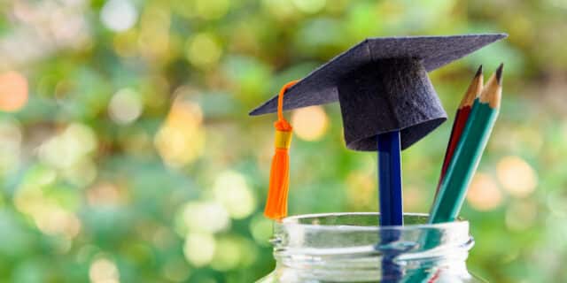 Back to school or graduate certificate program concept : Black graduation cap and a pencil in a bottle. Back to school is the period in which students prepares school supply for upcoming school year.