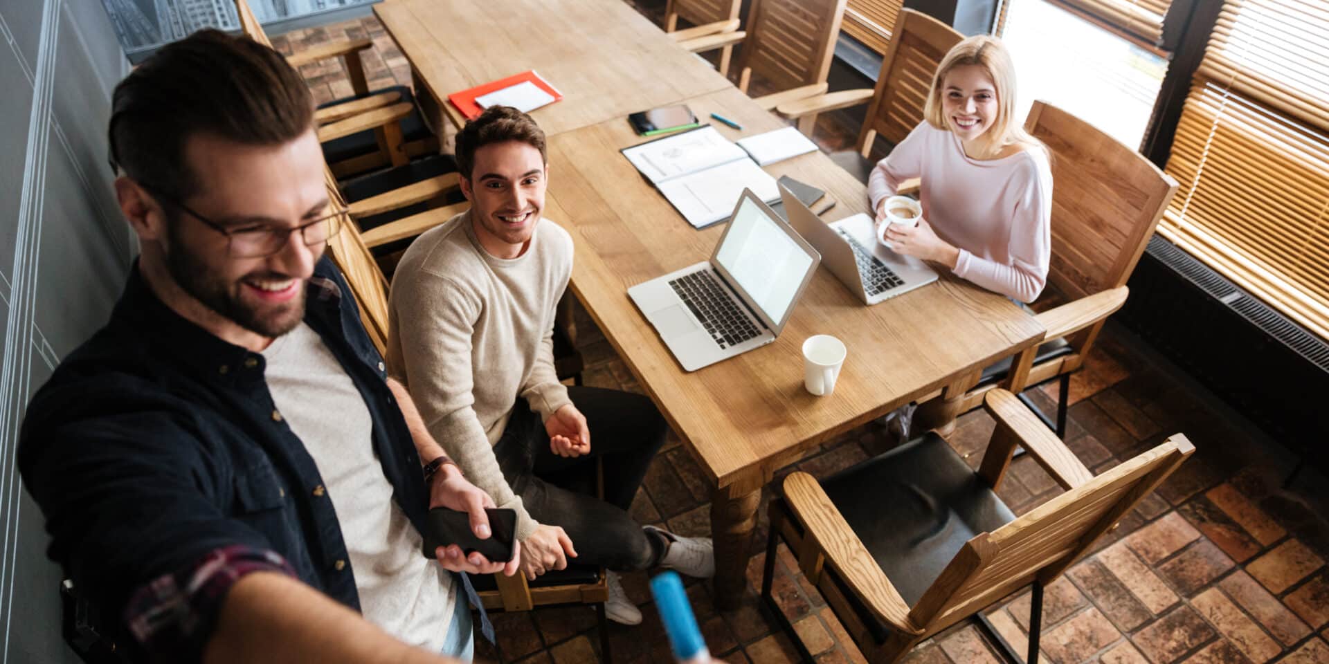 Young colleagues sitting while work with laptops and desk.
