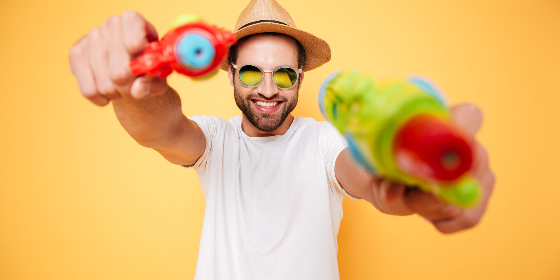 Happy young man holding toy water guns.