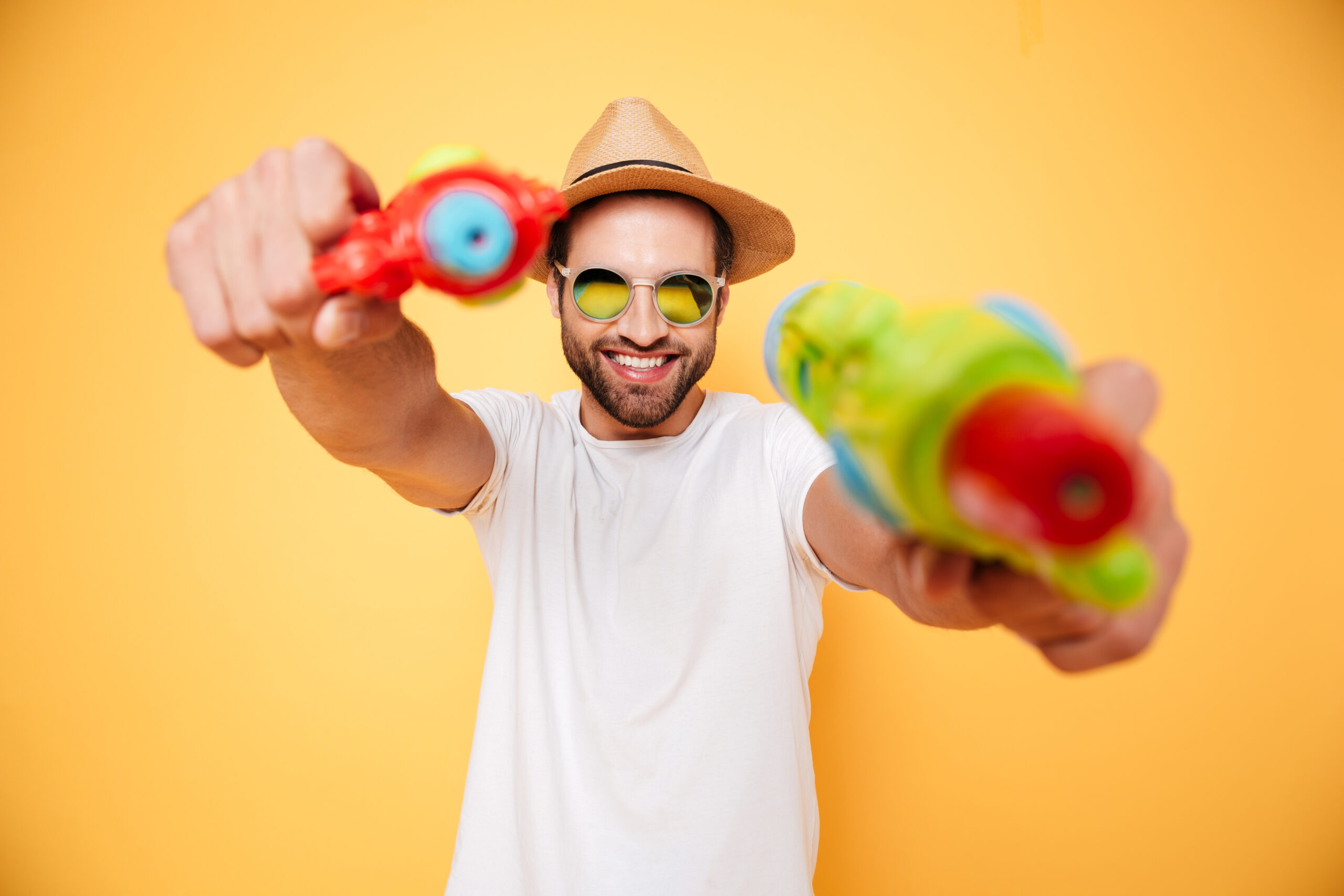 Happy young man holding toy water guns.