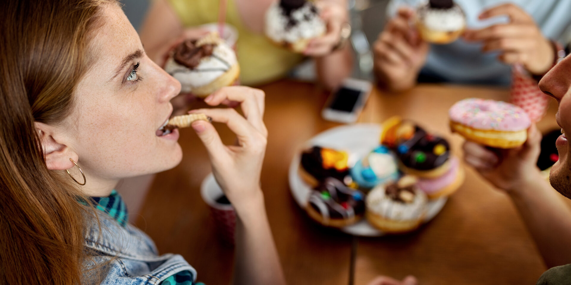 Young woman enjoying while eating donuts with friends.