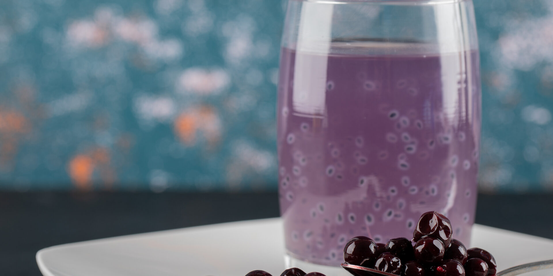 Blackcurrant confiture in a white saucer with a glass of juice around