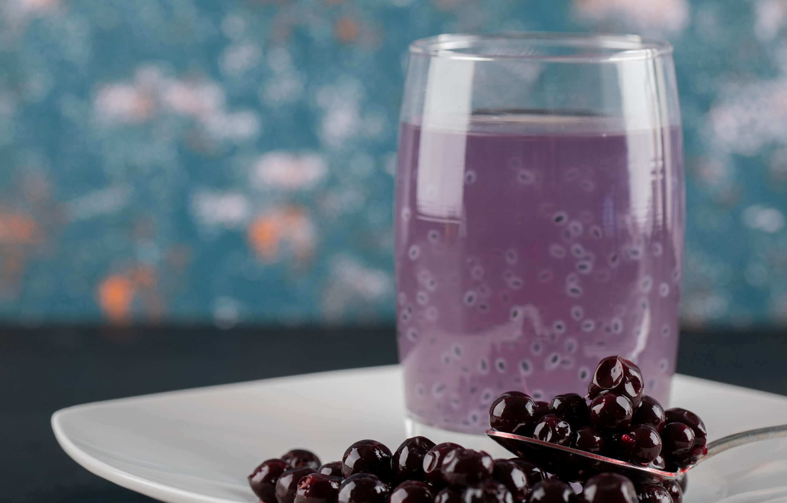 Blackcurrant confiture in a white saucer with a glass of juice around