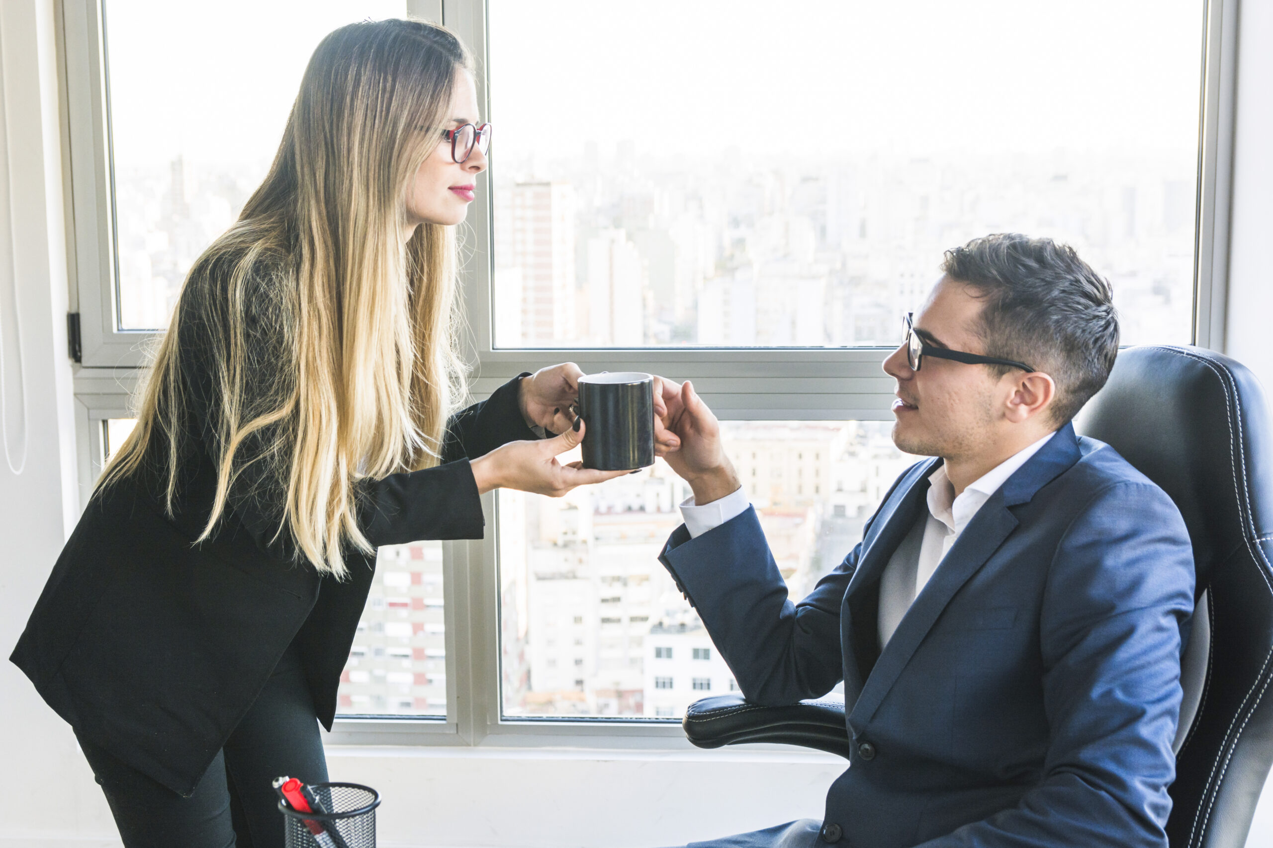 businesswoman-giving-coffee-her-boss-office