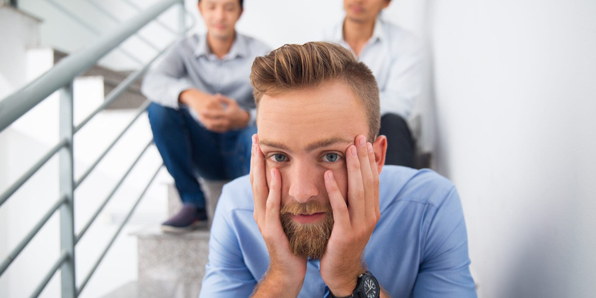 Tired man with head in hands and looking at camera