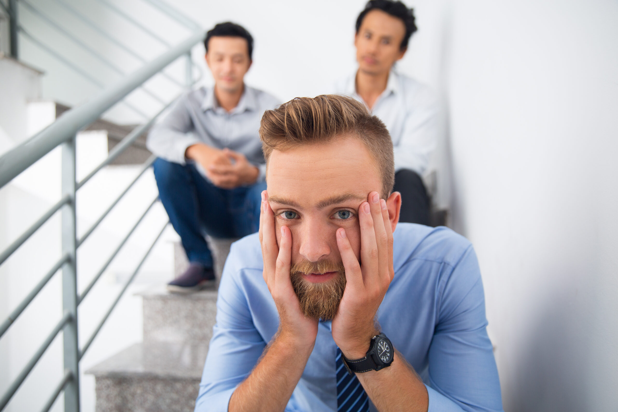 Tired man with head in hands and looking at camera