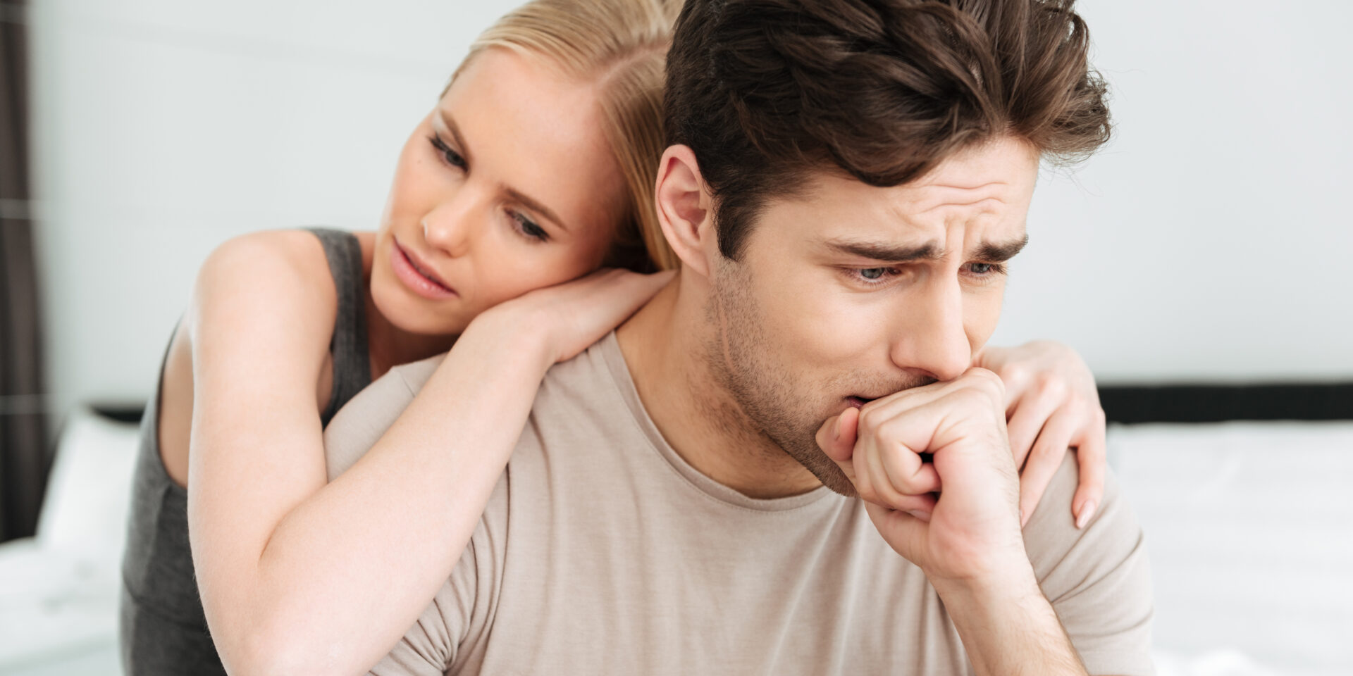 Pretty woman comfort her sad man while they sitting in bed