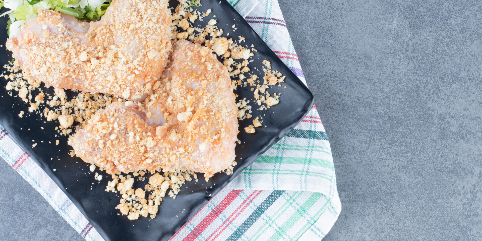 Raw chicken wing nuggets on black plate