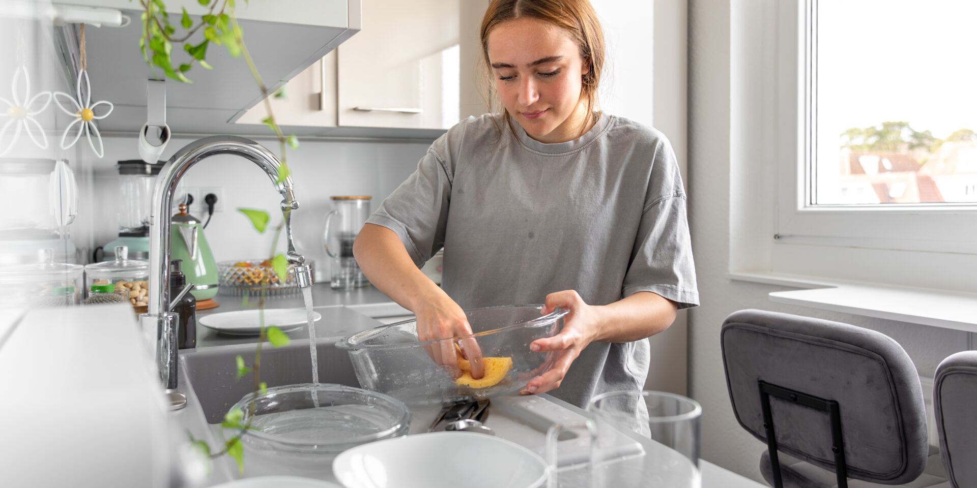 Teenage girl washing dishes. Washing dishes in the kitchen. Housework.