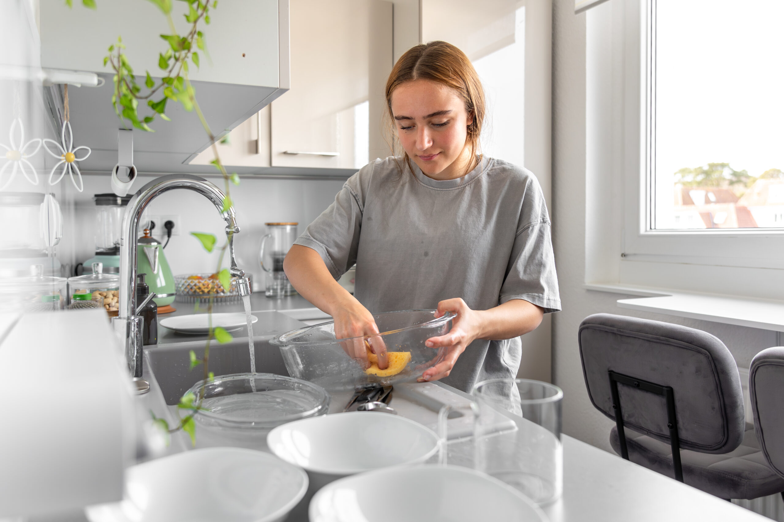 Teenage girl washing dishes. Washing dishes in the kitchen. Housework.