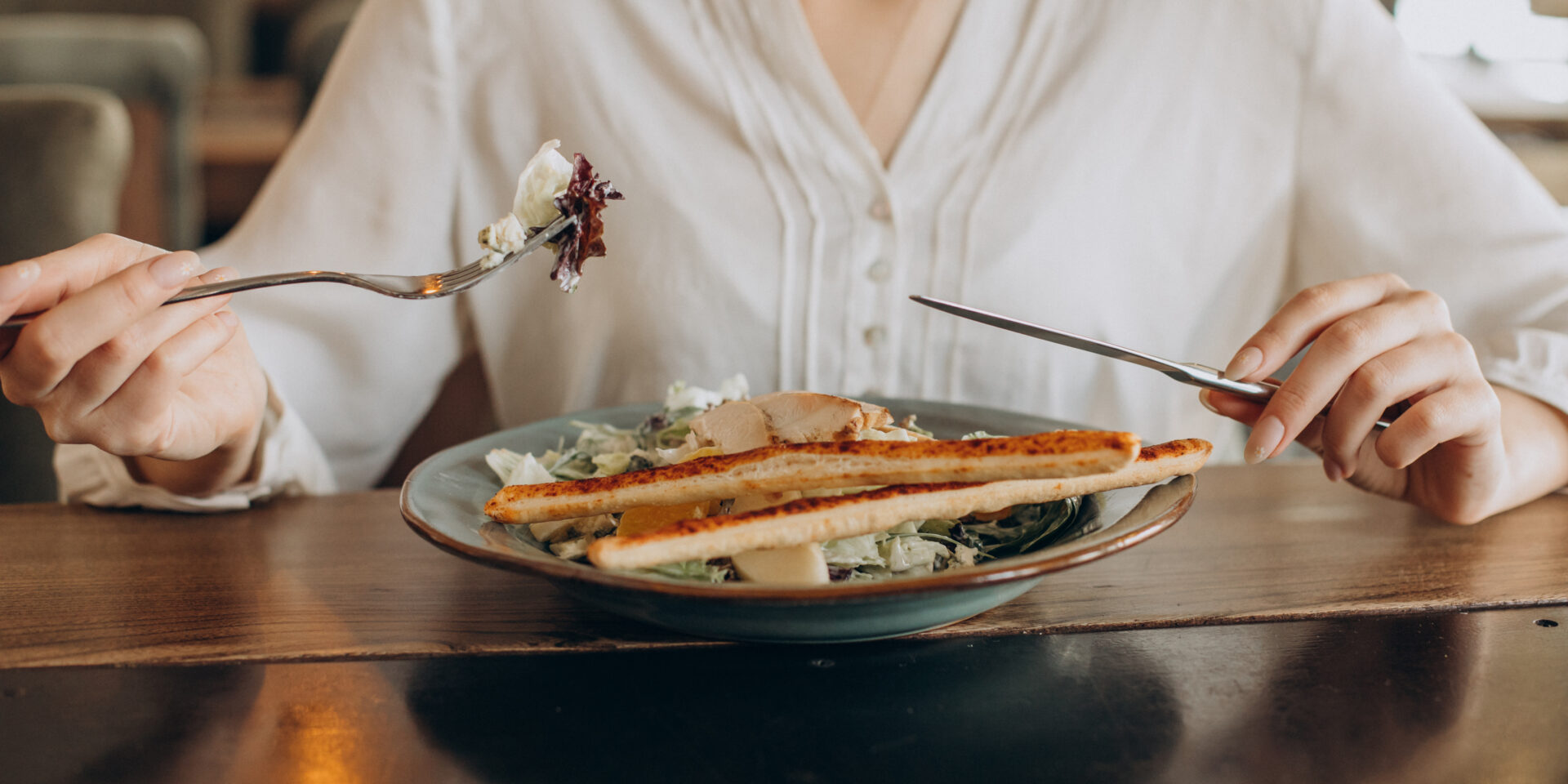 Woman having lunch in a cafe, eating salad close up