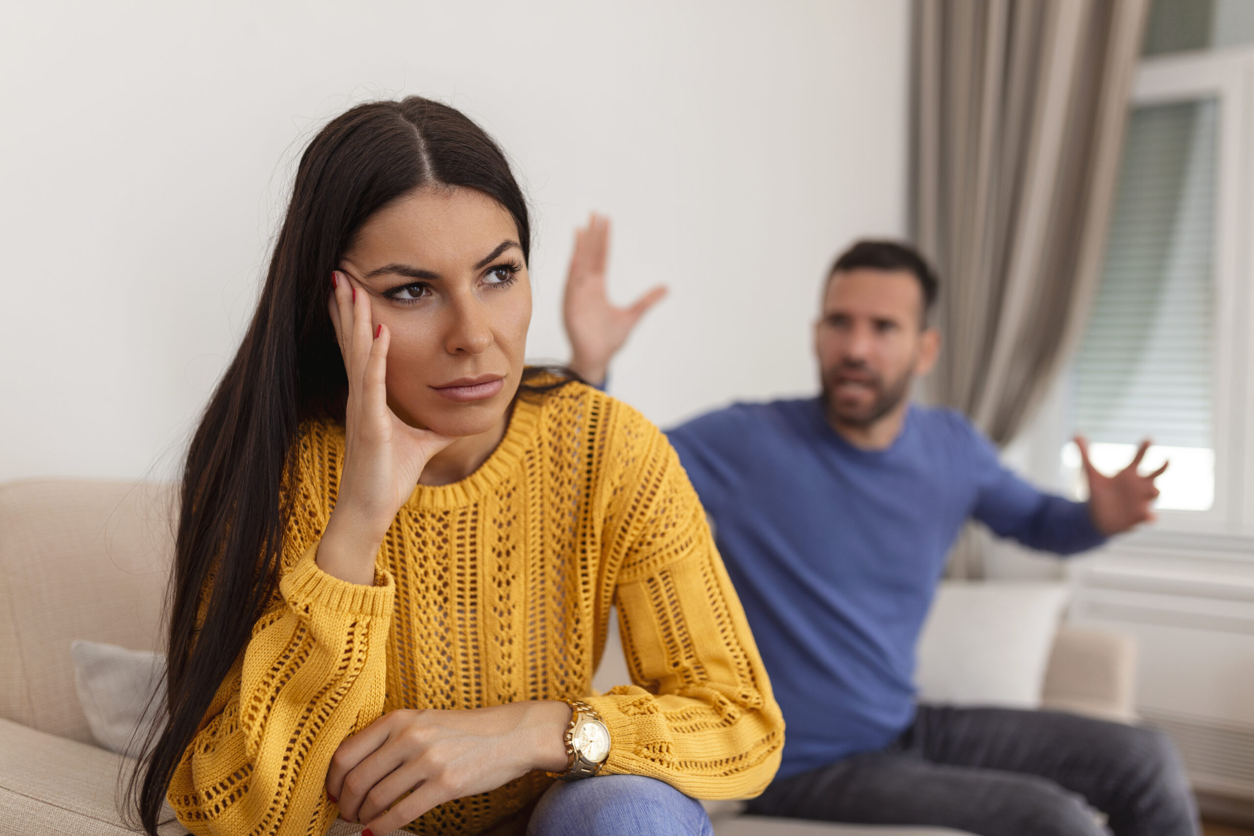 Young couple having argument – conflict, bad relationships. Angry fury woman. Angry young couple sit on couch in living room having family fight or quarrel suffer from misunderstanding