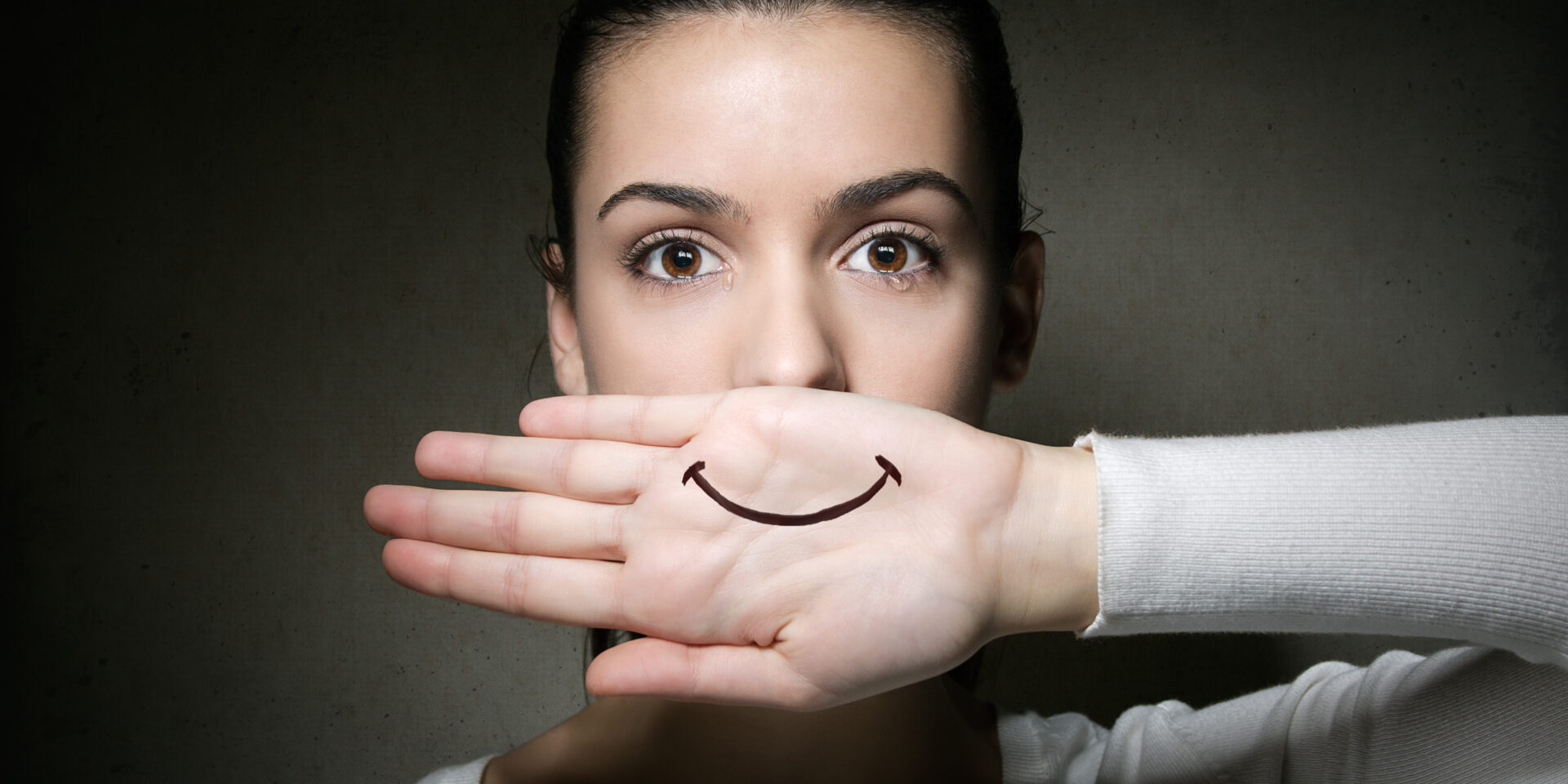 Portrait of young girl crying with her hand covering her mouth