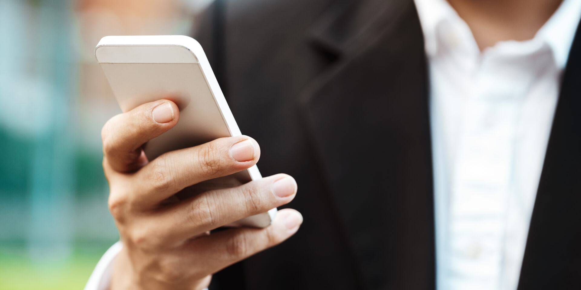 Close-up smart Business man wearing modern black suit and white shirt and texting on mobile smart phone