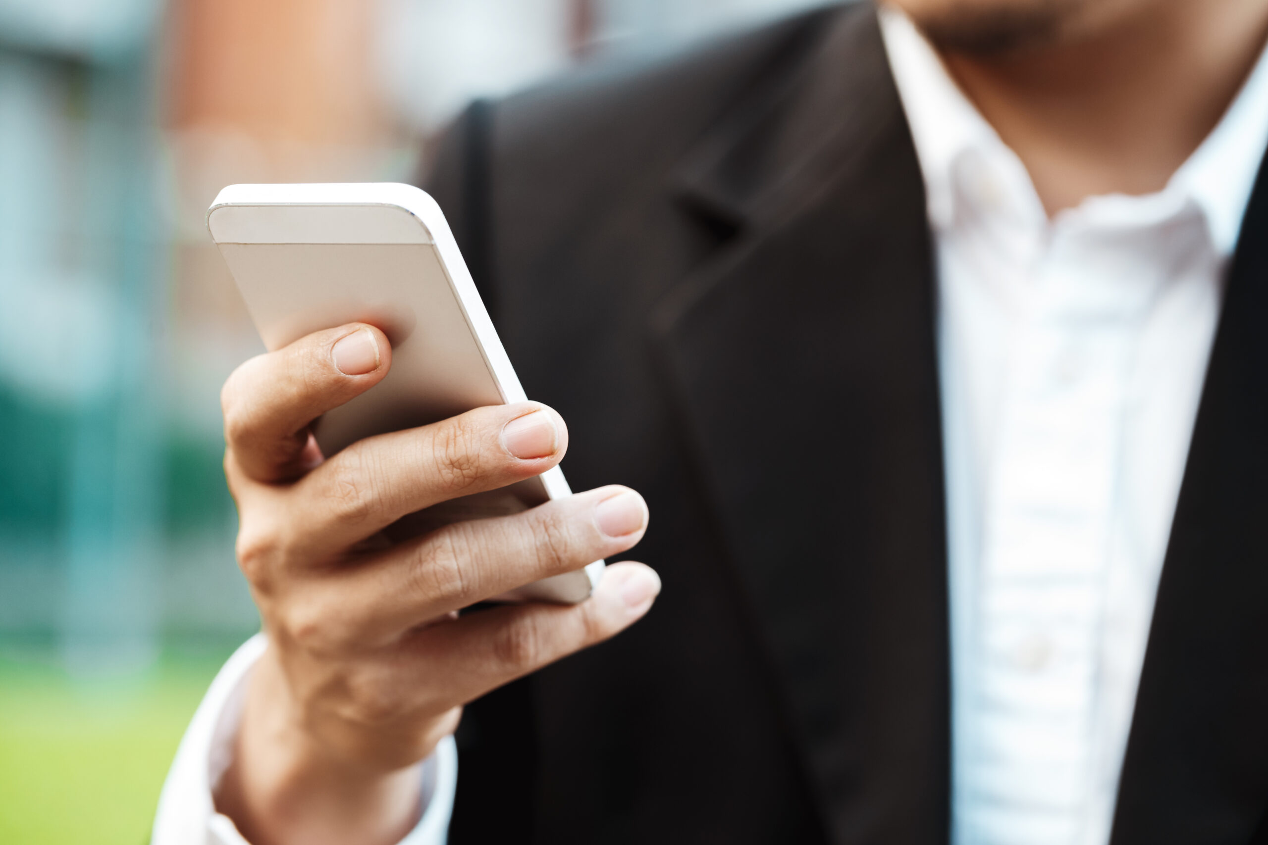 Close-up smart Business man wearing modern black suit and white shirt and texting on mobile smart phone