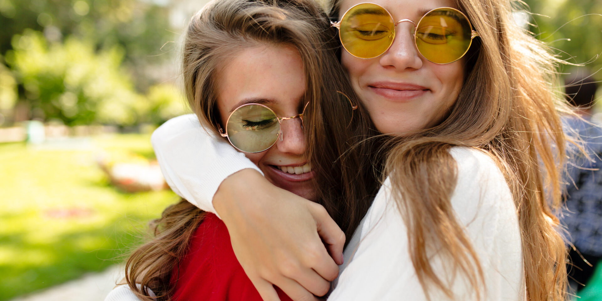 Lovely happy girls walking outside in sunny day. beautiful lovely woman in bright glasses hugging her friend and closed eyes with great smile, best friends, sisters, posivite mood