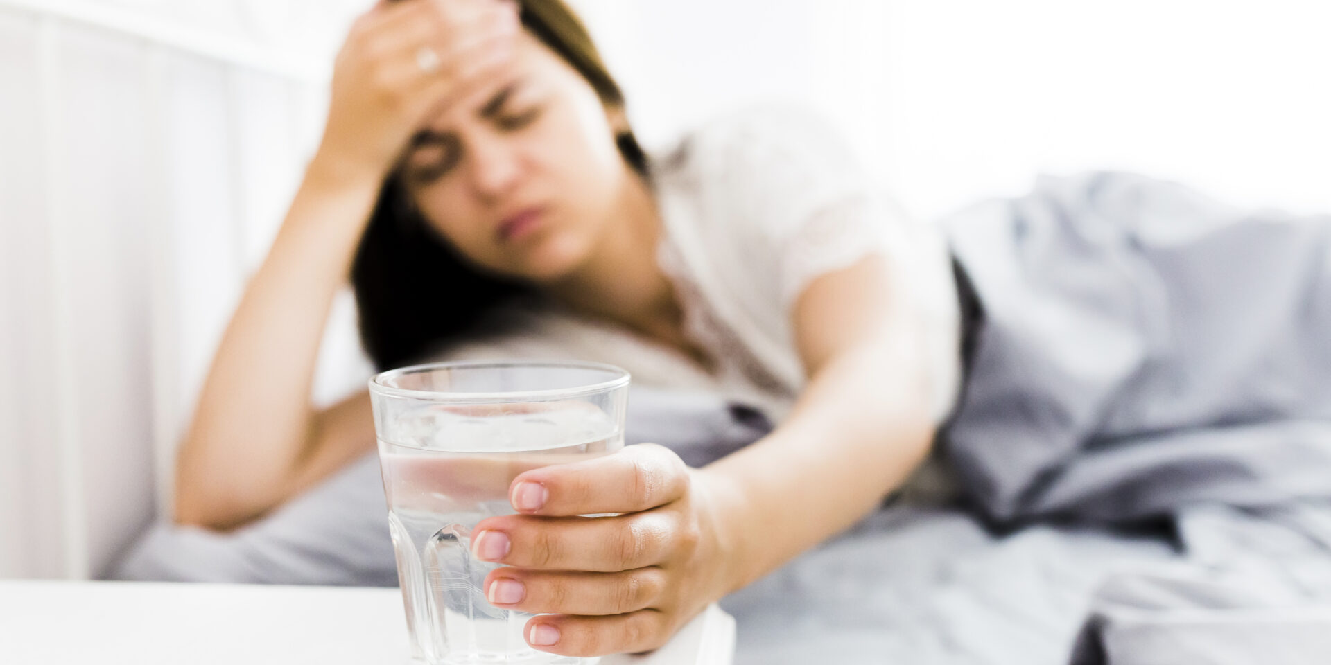 woman-with-headache-taking-glass-water