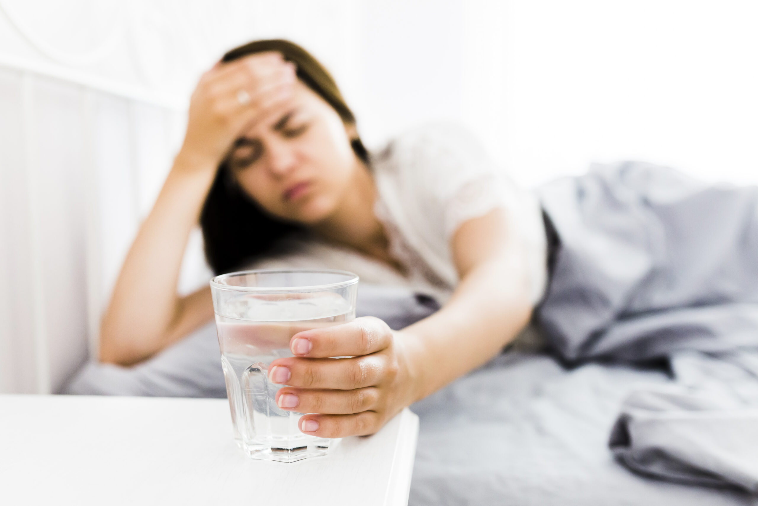 woman-with-headache-taking-glass-water