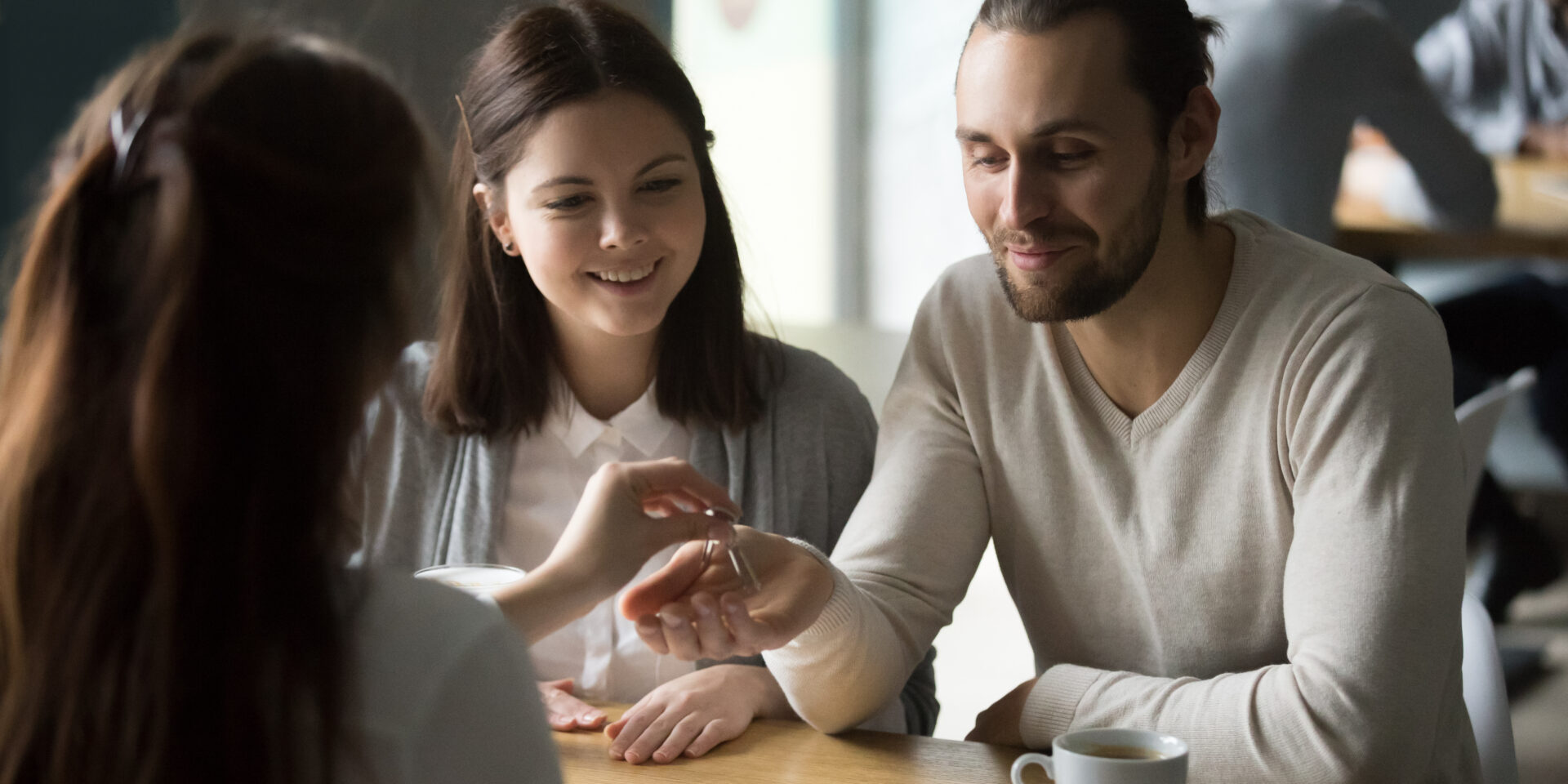 Happy millennial couple getting keys to new house from realtor