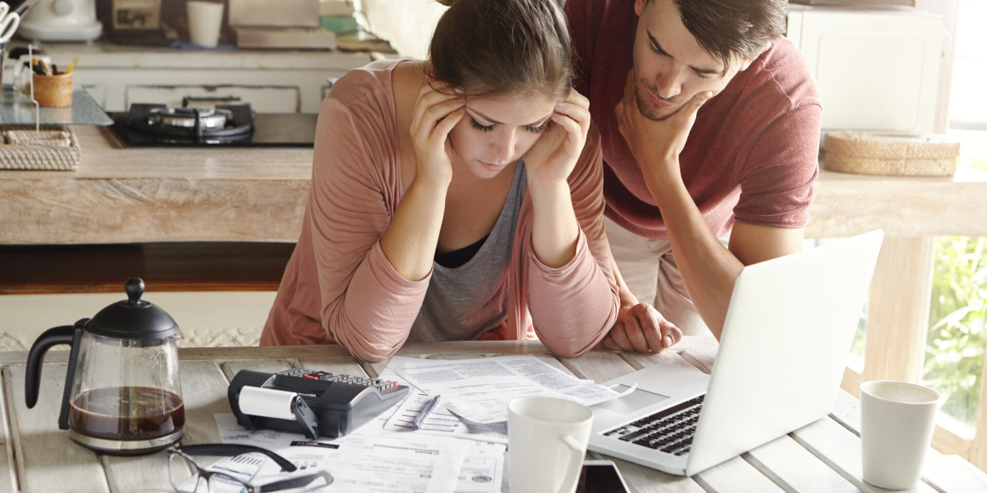 Stressed young Caucasian couple facing financial problems, not able to pay off their loan because of many debts. Woman with headache and worried man feeling stress, reading notification from bank