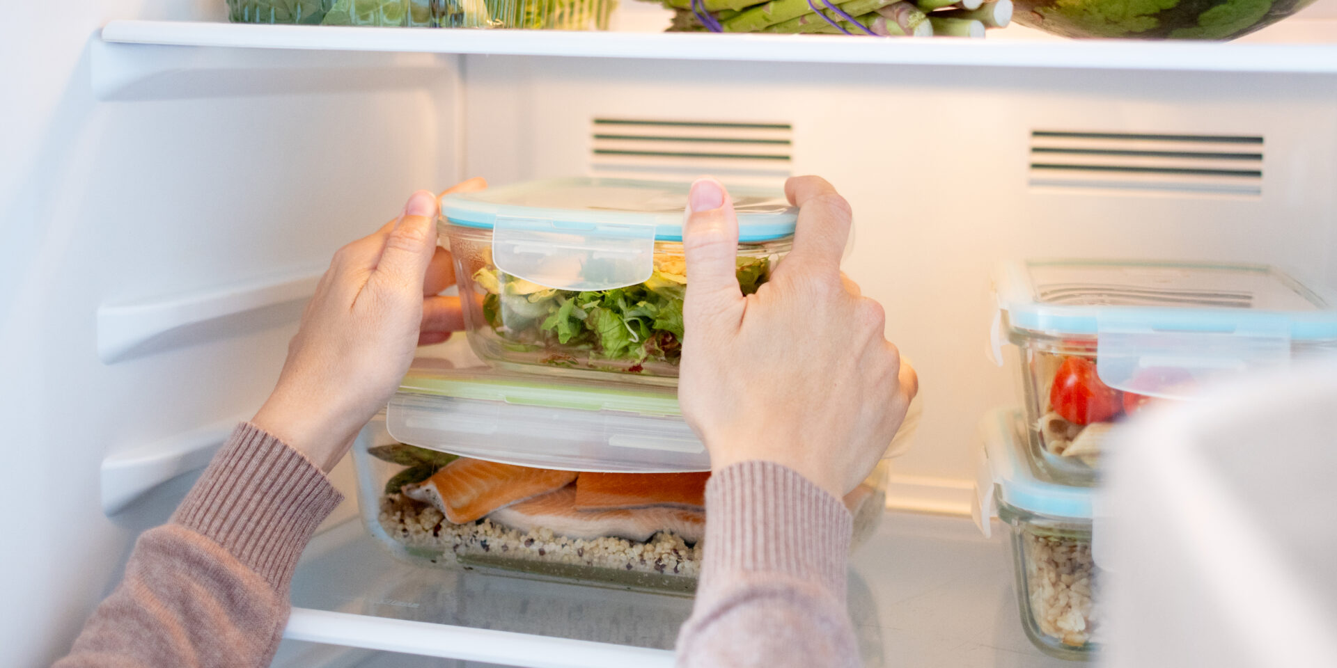 Woman Organizing Healthy Meal Prep Containers in Refrigerator at Home