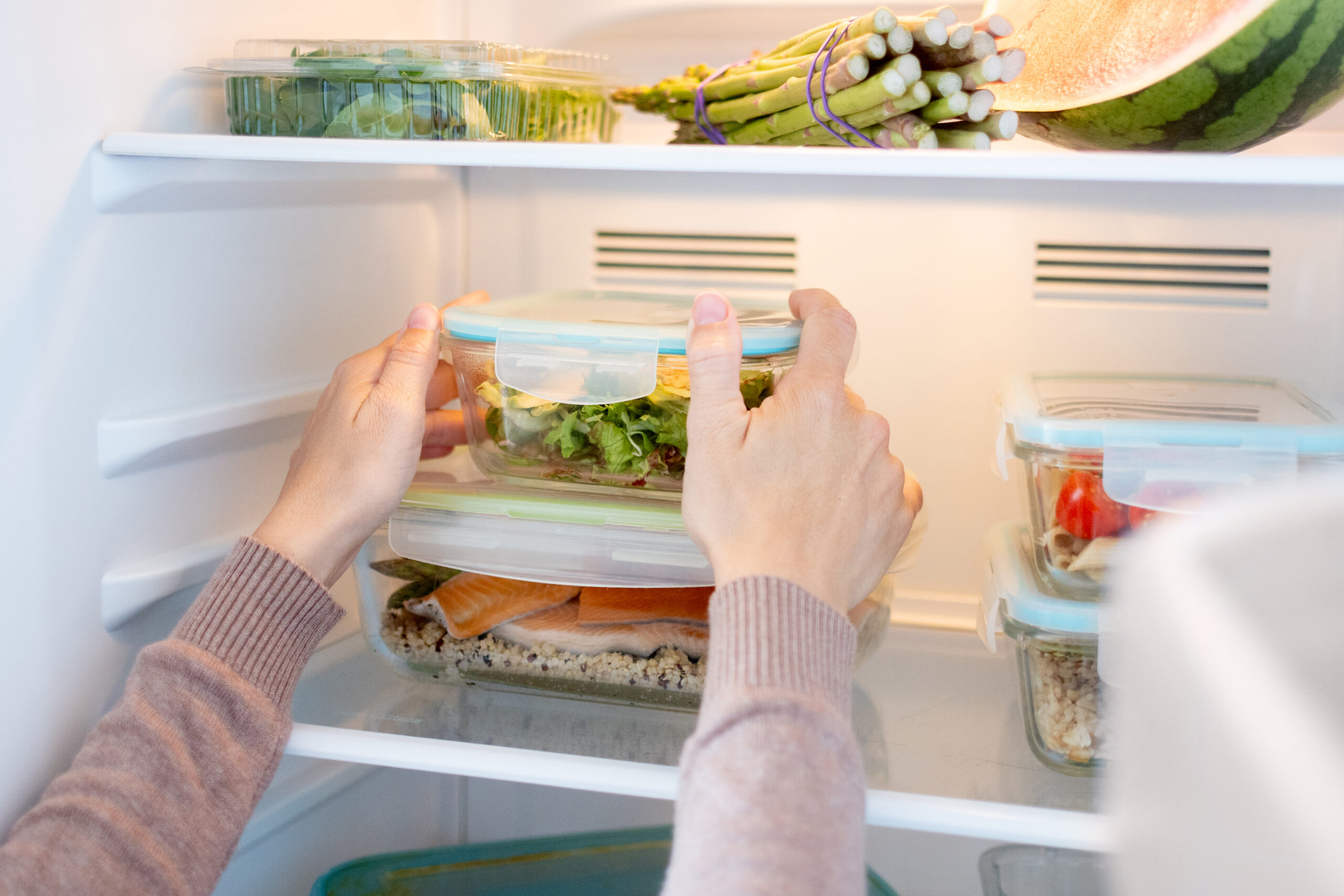 Woman Organizing Healthy Meal Prep Containers in Refrigerator at Home
