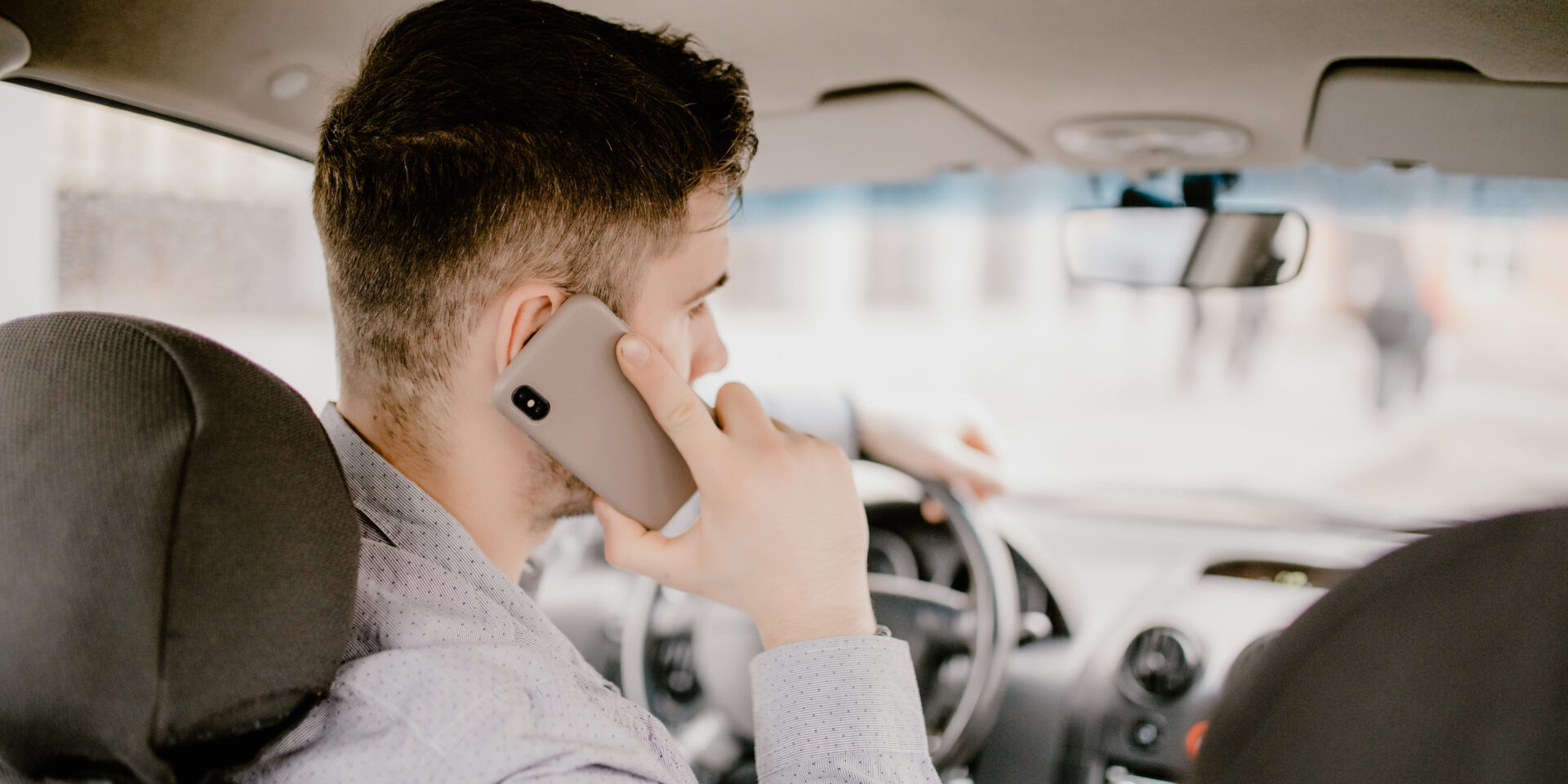 Young handsome man talking on cell phone while driving and overt