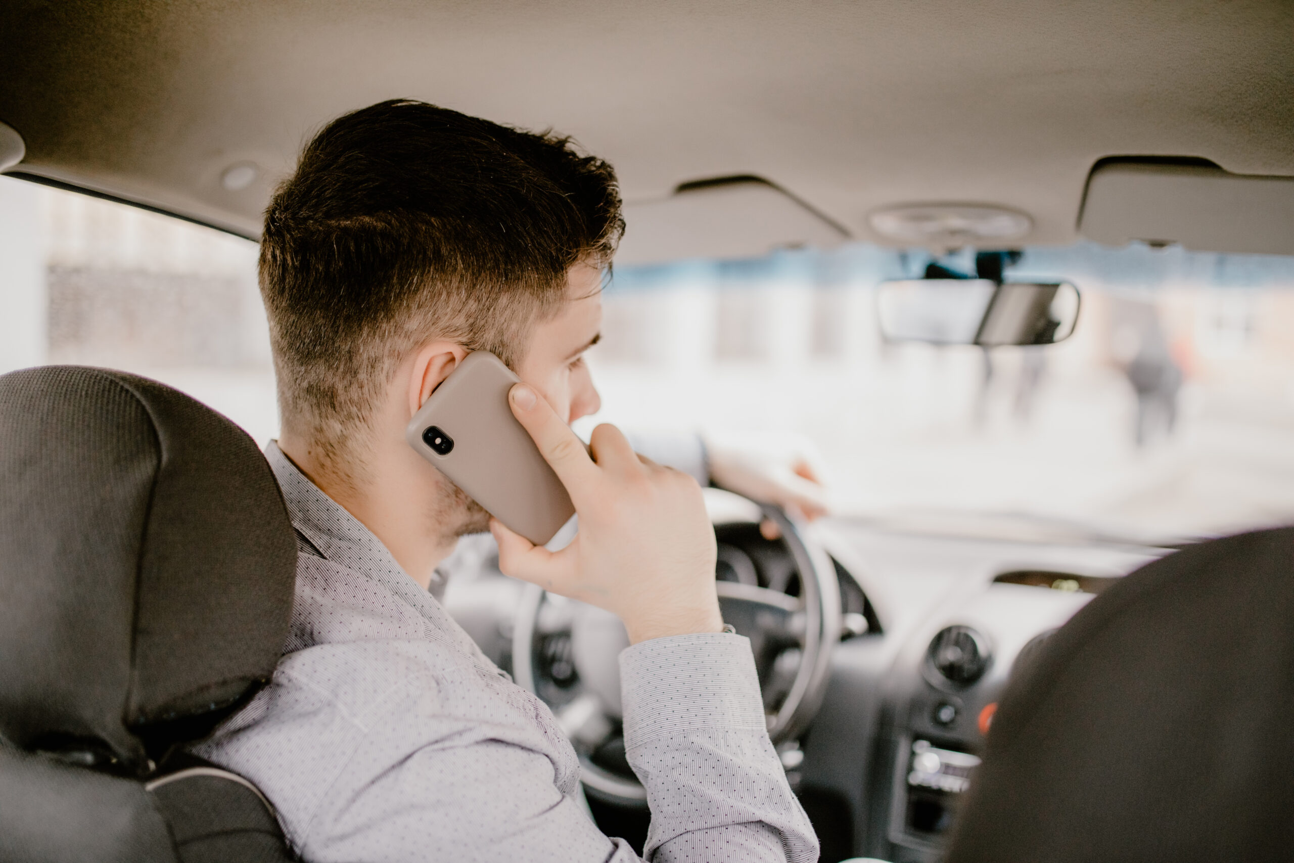 Young handsome man talking on cell phone while driving and overt