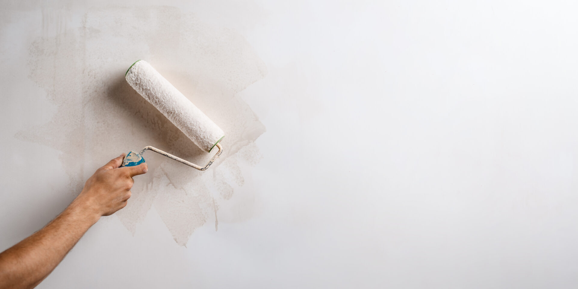Close up of hand painting wall with roller. Copy space.