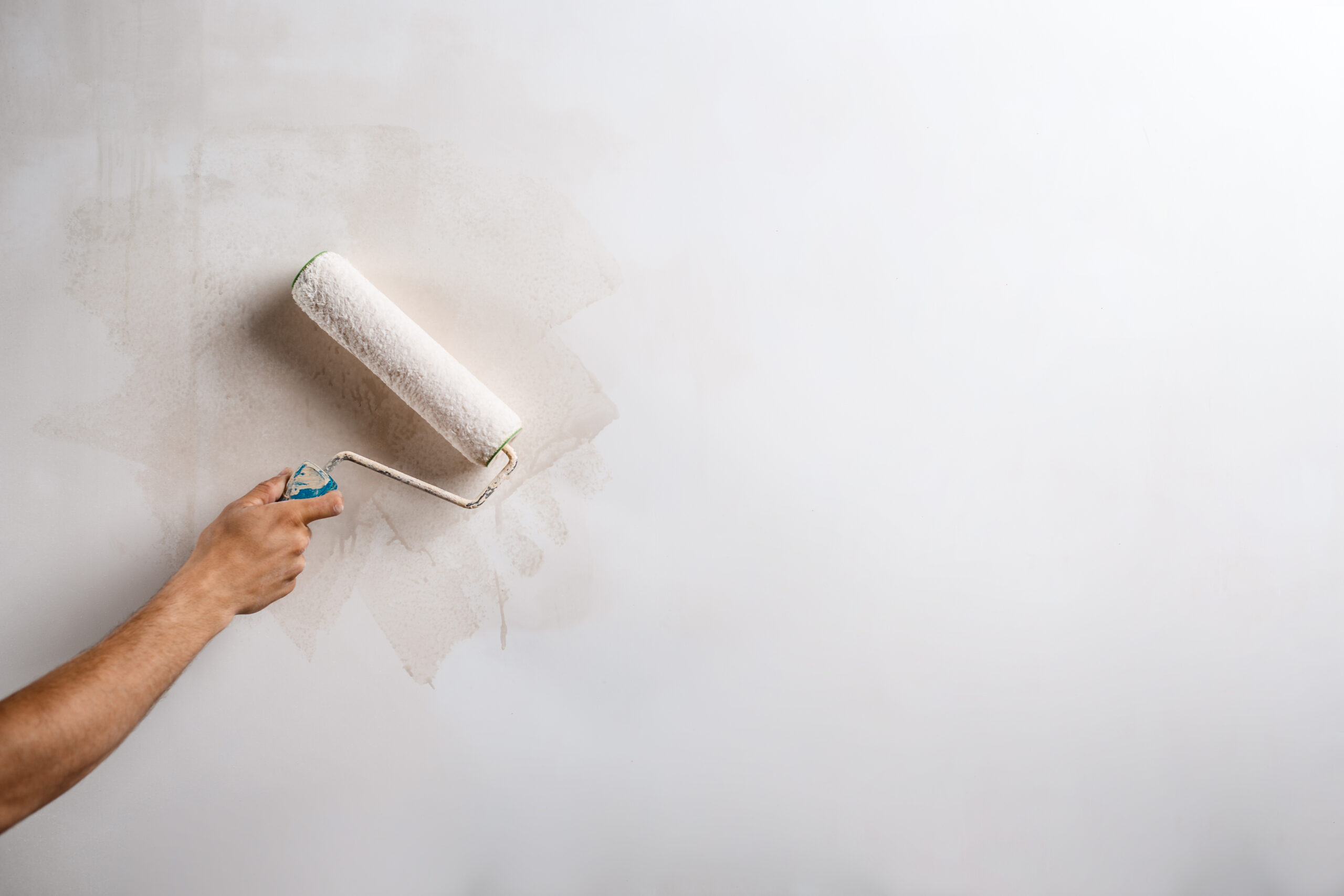Close up of hand painting wall with roller. Copy space.