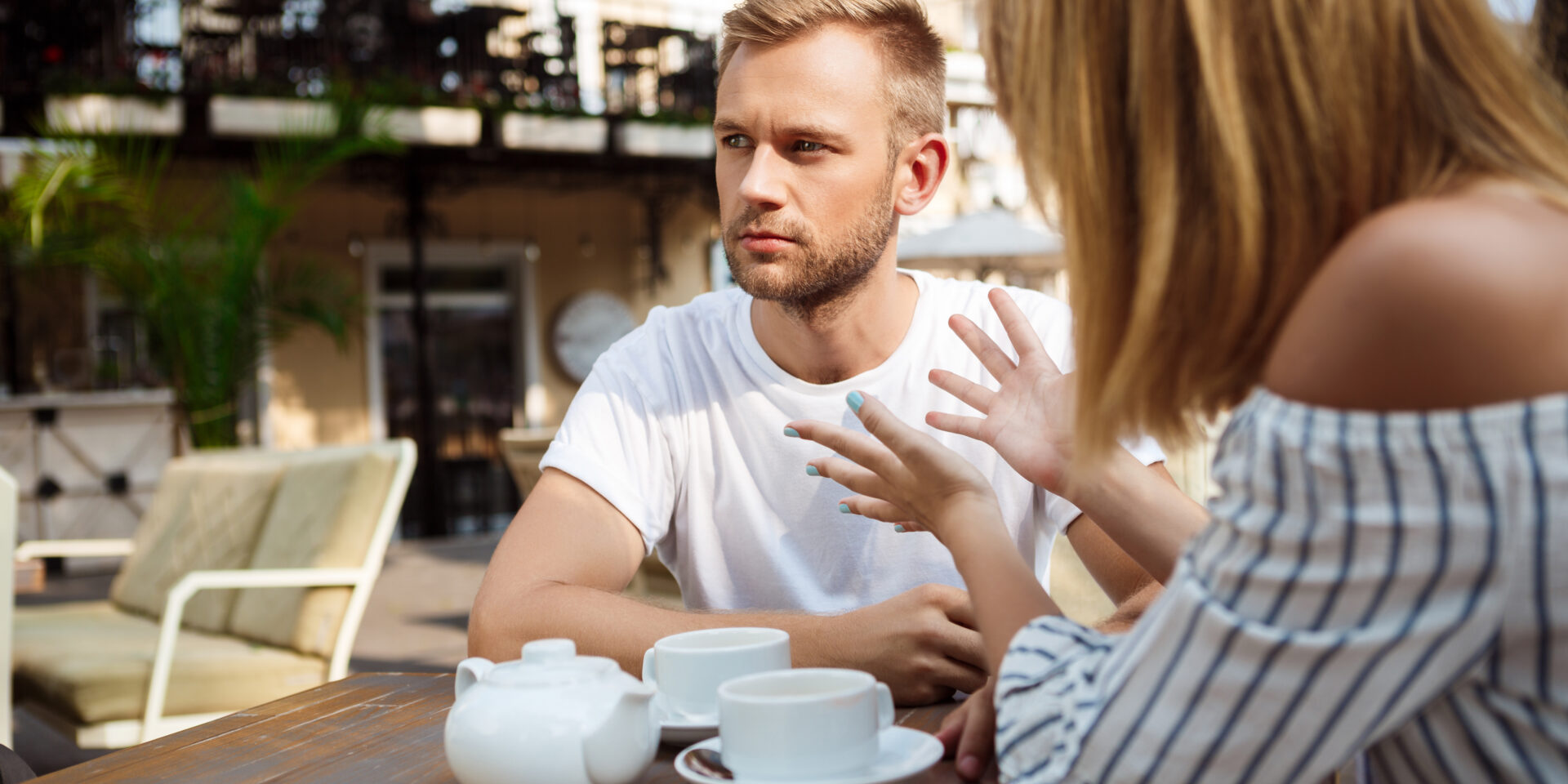 Young beautiful couple quarreling, sitting in cafe.
