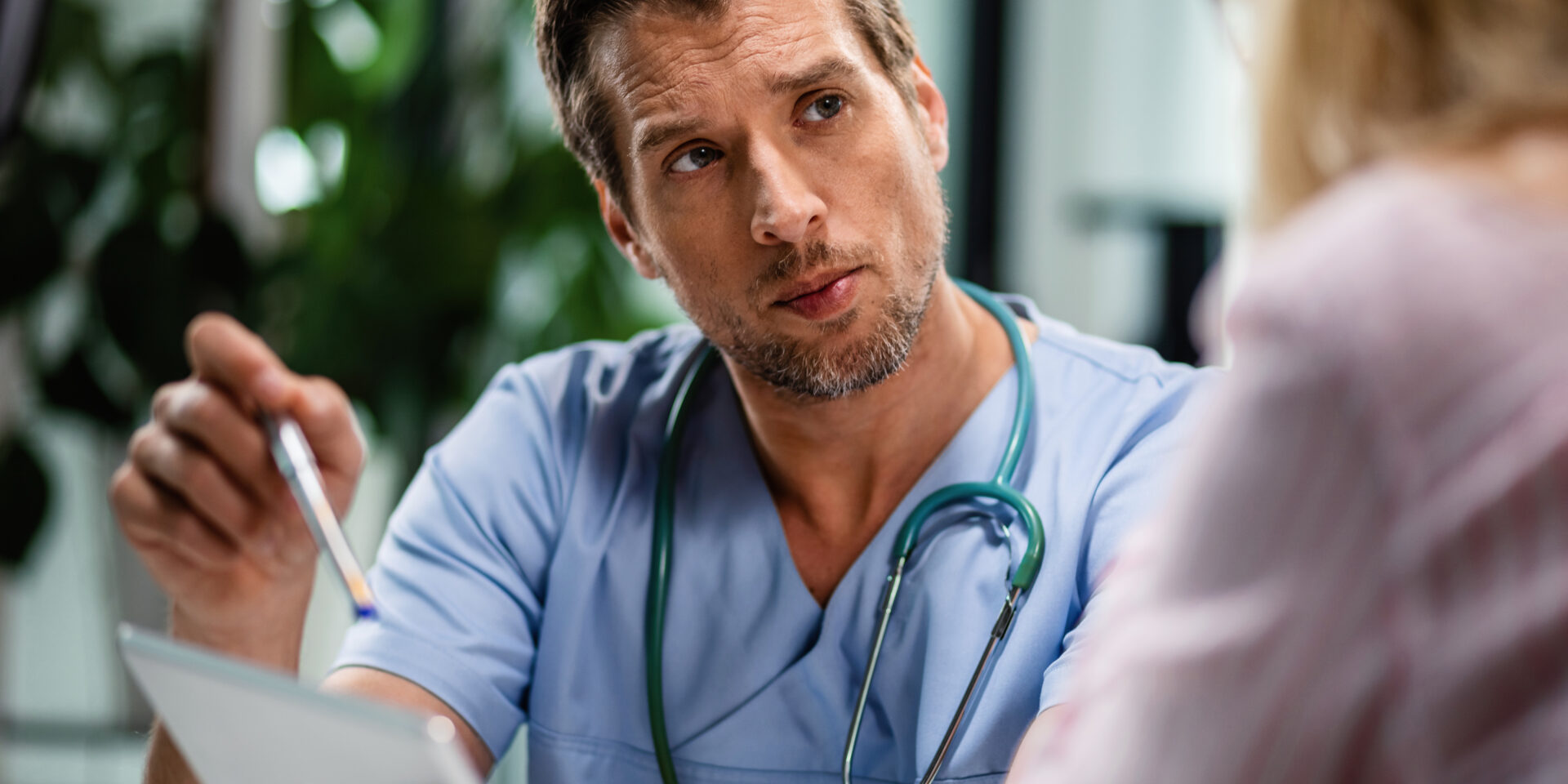 General practitioner using digital tablet while having consultation with his patient.