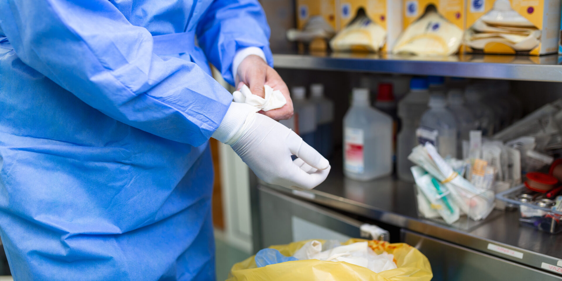 Male surgeon removing surgical gloves in operation theater at hospital